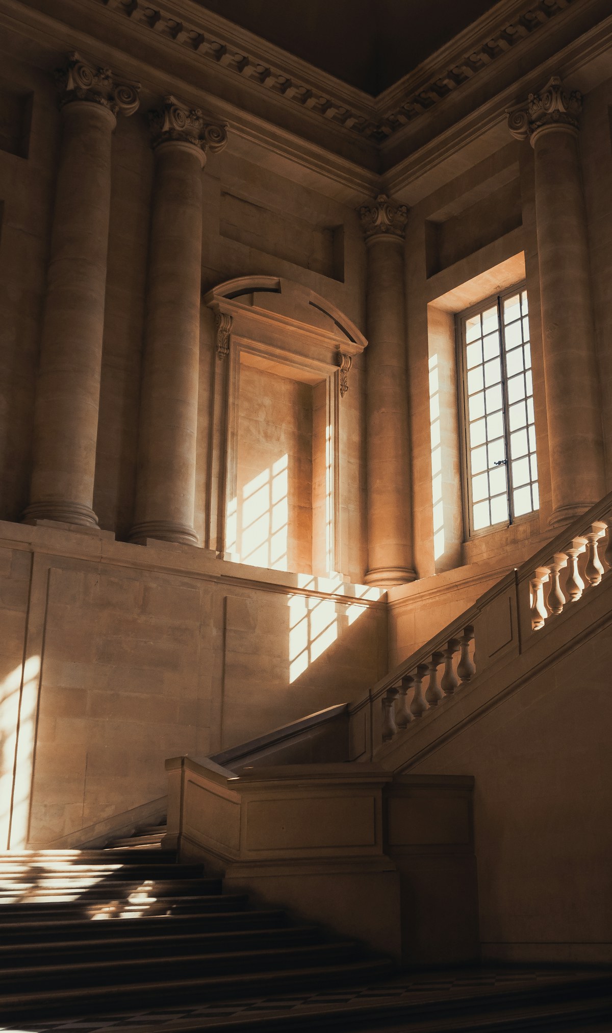 A sunlit stone staircase in a classical interior
