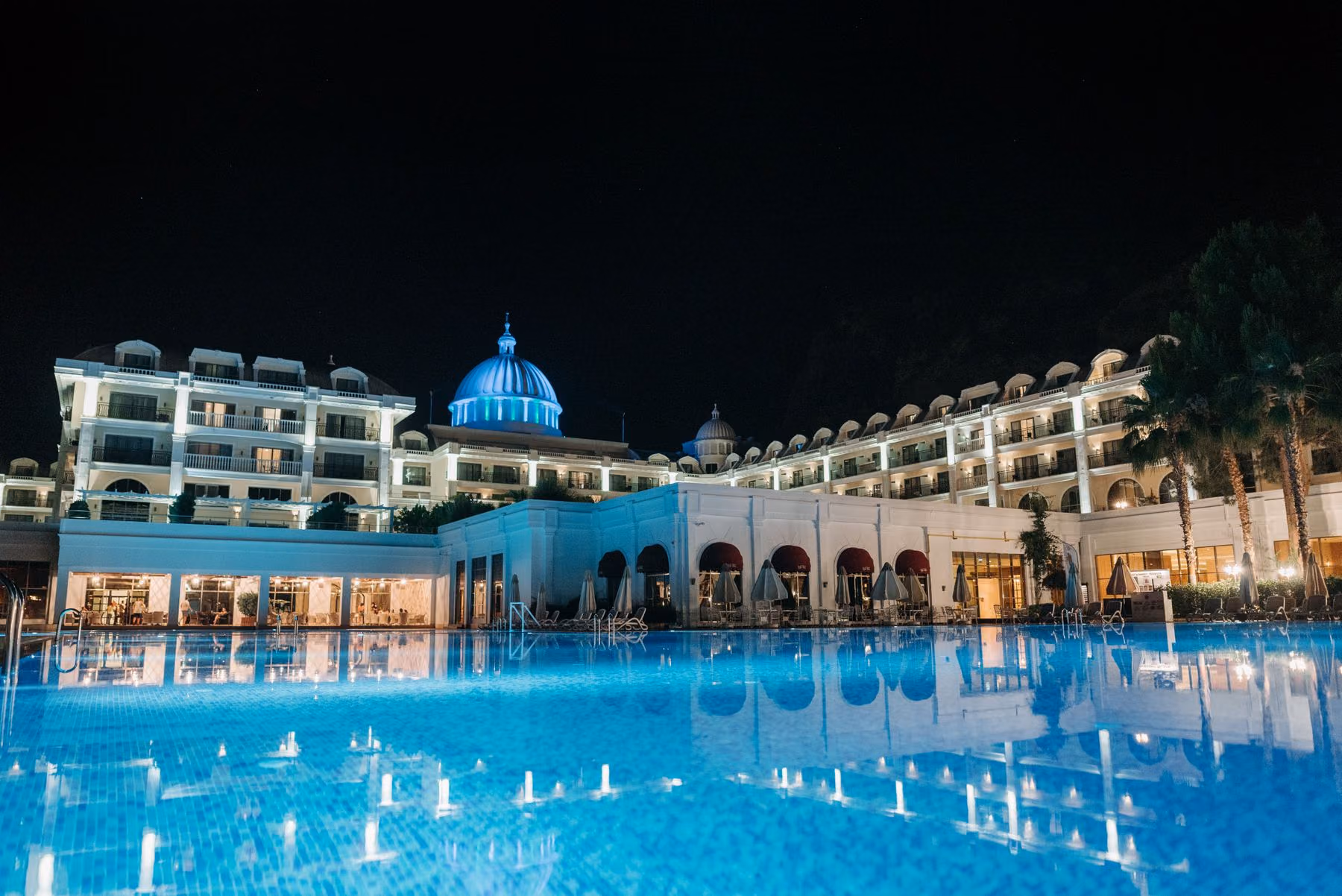 A resort hotel and illuminated pool after dark