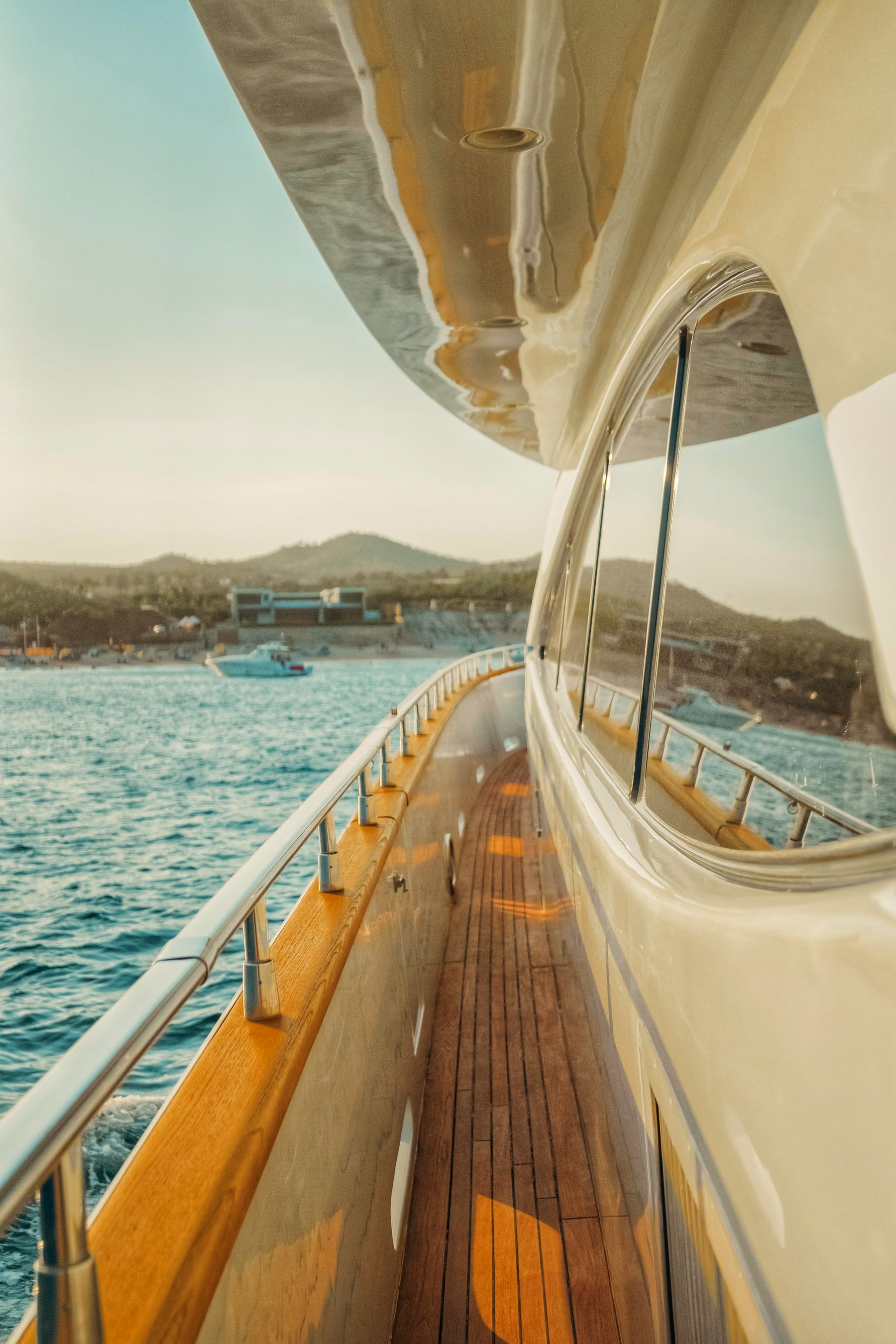 The polished deck of a yacht overlooking a quiet coastline